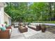 Outdoor patio area with comfortable seating around a fire pit, surrounded by lush greenery and mature trees at 1305 Kelly Nelson Dr, Lawrenceville, GA 30043
