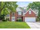 Charming two-story brick home with a well-manicured lawn, a white door, and an attached two-car garage at 1305 Kelly Nelson Dr, Lawrenceville, GA 30043