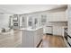 Modern kitchen with white cabinets, stainless steel appliances, a center island, and an adjacent living area at 4172 Cedar Commons Way, Conley, GA 30288