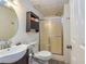 Compact bathroom features a round mirror, shower with sliding glass doors, and functional storage shelf at 120 Majesty Ln, Fayetteville, GA 30215