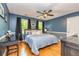 Bedroom with blue walls, hardwood floors, a ceiling fan, and two windows with dark curtains at 120 Majesty Ln, Fayetteville, GA 30215