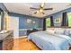 Bedroom with blue walls, hardwood floors, a ceiling fan, and two windows with dark curtains at 120 Majesty Ln, Fayetteville, GA 30215
