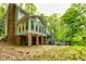 Back exterior view highlighting a two-story home with a brick chimney and multilevel decks among lush trees at 120 Majesty Ln, Fayetteville, GA 30215