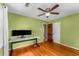This bedroom features light green walls, hardwood floors, a ceiling fan, and a sturdy work desk at 3541 Castlehill Ct, Tucker, GA 30084