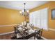 Bright dining room featuring modern chandelier, wooden floor, window with wooden shutters, and yellow walls at 2056 Merle Se Dr, Conyers, GA 30013