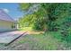 View of the backyard with stone patio, lawn and a line of trees along the back of the property at 7384 Birch Hollow Pl, Douglasville, GA 30134