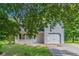 Charming home exterior with a front porch and attached garage, framed by lush trees and landscaped lawn at 7384 Birch Hollow Pl, Douglasville, GA 30134
