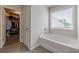 Bathroom showcasing a soaking tub, large window, and an open doorway to walk-in closet at 739 Woodstock Grove Dr, Woodstock, GA 30188