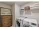 Functional laundry room with modern appliances and a rustic wooden cabinet for storage at 739 Woodstock Grove Dr, Woodstock, GA 30188