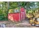 Image of a red storage shed in the backyard with a gray shingle roof and a lawnmower nearby at 854 Parkway Se Dr, Smyrna, GA 30080