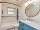 Bathroom featuring blue vanity, subway tile shower, and a round mirror at 2191 Fairfield Se St, Smyrna, GA 30080