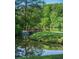 Picturesque pond featuring a wooden bridge, surrounded by lush greenery and reflecting the sky at 225 Lakeview W Rdg, Roswell, GA 30076