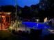 Night view of a backyard pool, fully fenced, with a slide and lounge chairs and illuminated by landscape lighting at 424 Lake Point Trce, Canton, GA 30114