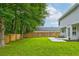 A spacious backyard with lush green grass, a wooden fence, and landscaping stones at 7006 Mahonia Place, Stonecrest, GA 30038