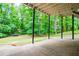 View of the tree-lined backyard from covered patio with black support beams at 9691 Squirrel Wood Run, Douglasville, GA 30135