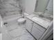Well-lit bathroom featuring marble-style wall and floor tiles, modern vanity with granite countertop, and tub with shower at 9691 Squirrel Wood Run, Douglasville, GA 30135