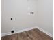 Clean laundry room with wood-look flooring, light gray walls, and necessary outlet/plumbing for appliances at 9691 Squirrel Wood Run, Douglasville, GA 30135