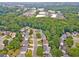 An aerial view of a neighborhood with tree-lined streets and a mix of residential houses and commercial buildings at 310 Arbor Creek Trl, Roswell, GA 30076