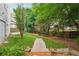 A stone walkway leads through the lush green backyard with mature trees and access to the home's deck and patio at 310 Arbor Creek Trl, Roswell, GA 30076