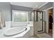 Luxurious bathroom featuring soaking tub, glass-enclosed shower, and neutral tile at 310 Arbor Creek Trl, Roswell, GA 30076