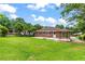 Grassy backyard with a brick home, concrete patio, and mature trees, ideal for entertaining and enjoying the outdoors at 821 Springvalley Dr, Forest Park, GA 30297