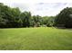 Vast backyard with lush green grass, mature trees, and a small red shed, offering ample space for recreation at 1809 Brandi Ln, Loganville, GA 30052