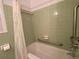 Bathroom featuring mint green tiles, a bathtub with shower, and convenient grab bars at 3098 Henderson Mill Rd, Atlanta, GA 30341