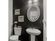 Stylish powder room features a modern pedestal sink, oval mirror, and black accent wall with decorative art at 7207 Gladstone Cir, Stonecrest, GA 30038
