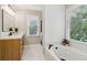 This bathroom features a large tub, a light wood vanity, and a bright window at 1006 Amberton Ln, Powder Springs, GA 30127