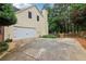 Side exterior of home with a large driveway leading to a two-car garage with green trees at 1006 Amberton Ln, Powder Springs, GA 30127