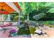 Outdoor backyard features a deck with a waterfall feature, lush landscaping, and mature trees at 570 Hunt River Way, Suwanee, GA 30024