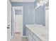 Light blue bathroom with a double sink vanity, framed mirror, and a doorway leading to a shower/tub combo at 570 Hunt River Way, Suwanee, GA 30024