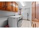Functional laundry room with wooden cabinets, white appliances, and tiled floor near a wooden door at 570 Hunt River Way, Suwanee, GA 30024