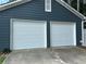 View of a two-car garage with white doors and dark siding at 354 Dublin Way, Lawrenceville, GA 30044