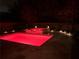 Night view of a backyard pool and hot tub area illuminated with atmospheric red lighting, creating a relaxing ambiance at 123 Meridian Dr, Woodstock, GA 30188