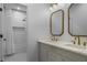 Bright bathroom featuring double vanity, framed mirrors, and a shower with white tile and gold fixtures at 2013 White Cypress Ct, Smyrna, GA 30082
