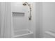 Shower featuring vertically stacked white tiles, built-in soap niche, and gold rainfall shower head at 2013 White Cypress Ct, Smyrna, GA 30082