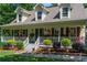 Inviting front porch adorned with hanging plants and decorative shrubs along the white picket railing, offering a cozy welcome at 2050 Lyda Ln, Loganville, GA 30052