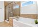 Bright bathroom featuring a glass enclosed shower and a separate tub, complemented by earth-toned tiling at 441 Spring View Dr, Woodstock, GA 30188
