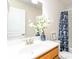 Bright bathroom with a single sink vanity, white flower decor and a shower-tub combination with curtain at 441 Spring View Dr, Woodstock, GA 30188