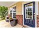 Cozy porch with seating beside a beautiful blue front door, brick accents, and tiled flooring at 441 Spring View Dr, Woodstock, GA 30188