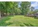Large backyard with lush green grass, mature trees, and a spacious deck area at 3812 Chattawood Dr, Duluth, GA 30096