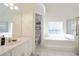 Bright bathroom featuring a large soaking tub, vanity with sink, and tiled floors at 1441 Hada Ln, Lawrenceville, GA 30043