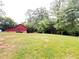 Large green backyard with mature trees, red barn, and covered storage area offers serene outdoor space at 776 Green Dr, Canton, GA 30114