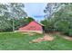 An old red barn shows a yard with green grass, and trees on a sunny day at 776 Green Dr, Canton, GA 30114