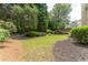 A large backyard with a tiered retaining wall, grass, and lush landscaping at 300 Brackin Trce, Grayson, GA 30017