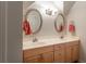 Bathroom featuring double sinks with modern fixtures, oval mirrors, and vanity cabinets, brightened by elegant lighting at 300 Brackin Trce, Grayson, GA 30017