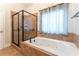 This bathroom features a glass-enclosed shower, a soaking tub with jets, and a window with light blue curtains at 300 Brackin Trce, Grayson, GA 30017