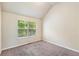Carpeted bedroom with a vaulted ceiling and a window that overlooks trees at 7946 White Oak Loop, Stonecrest, GA 30038