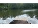 Waterfront view of the lake featuring a private wooden dock, mature trees reflected in the water at 4221 Riverlake Way, Snellville, GA 30039